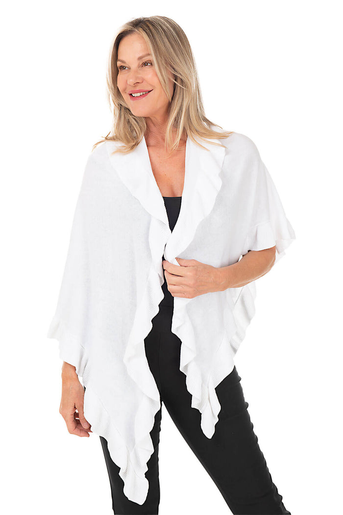 A woman wearing a white open front wrap sweater with ruffled rib-knit trim over a black top and black pants.