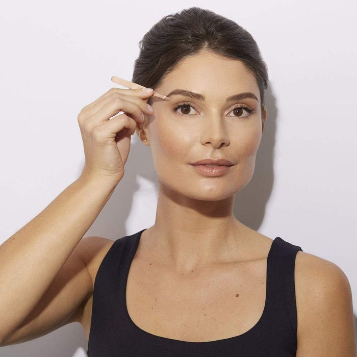 Woman using Petite Rose Gold Tweeze Set | Tweezerman to groom her eyebrows, demonstrating precise skincare and body care grooming in a simple, clean setting.