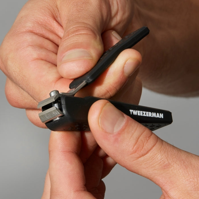 Close-up of hands holding and using the Precision Grip Toenail Clipper | Tweezerman, designed for precise and comfortable nail trimming.