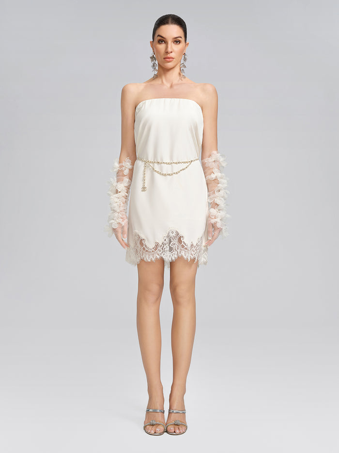 Elegant woman in a white strapless dress featuring delicate lace trim, floral sleeve embellishments, and a refined silhouette