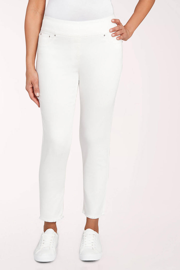 Person wearing white jeans and white sneakers on a light pink background