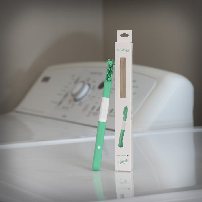Green silicone cleaning brush with packaging on a washing machine