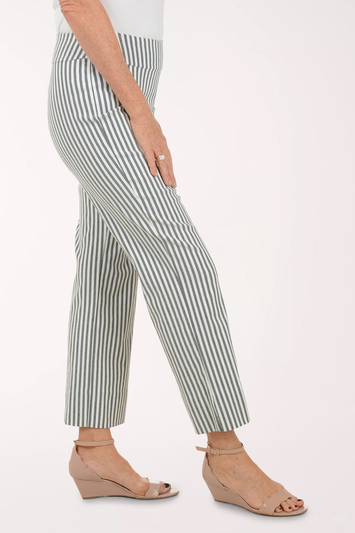 Woman wearing a white top with mesh sleeves and striped pants on a white background