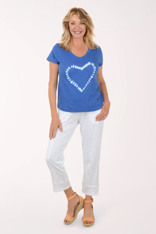 Woman wearing a blue t-shirt with a white heart design and white pants on a white background