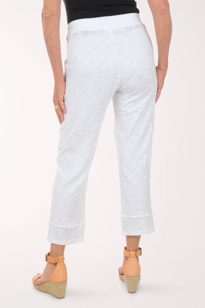Person wearing white pants on a plain background