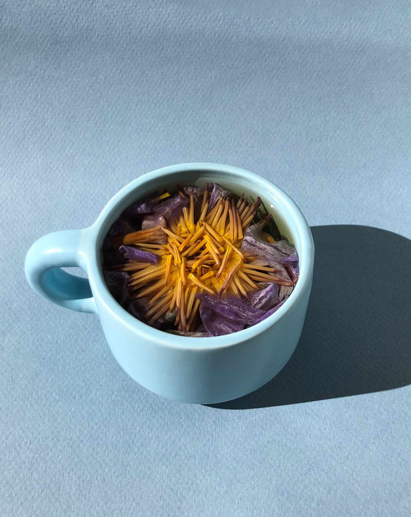 Light blue ceramic cup filled with dried yellow and purple flower petals, presented as part of the Floral Collection (Variety Box) | The Qi for a calming wellness experience.