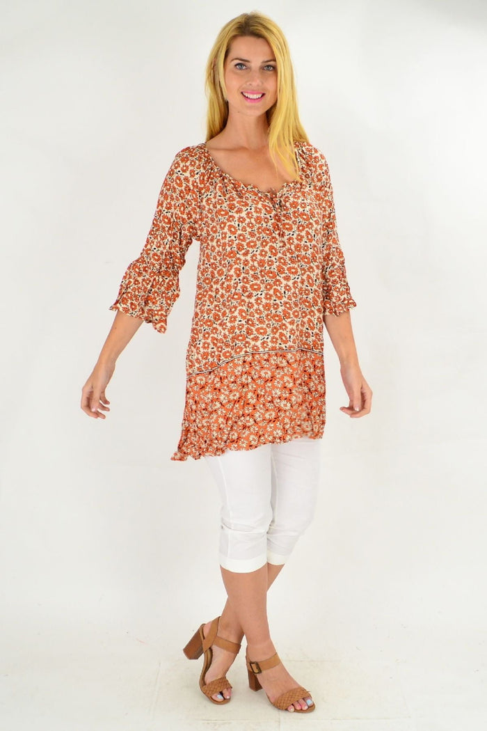 Hourglass fresh orange flower crinkle tunic top displayed on a hanger, showcasing its lightweight, textured fabric and vibrant floral design.