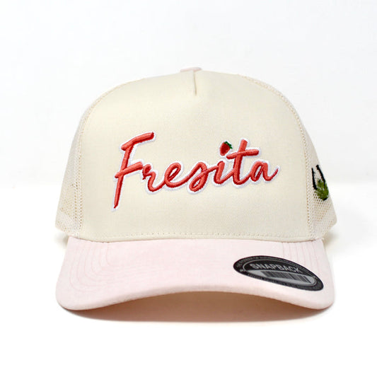Front view of cream and pink Fresita snapback cap with embroidered red script and small strawberry detail on the letter i