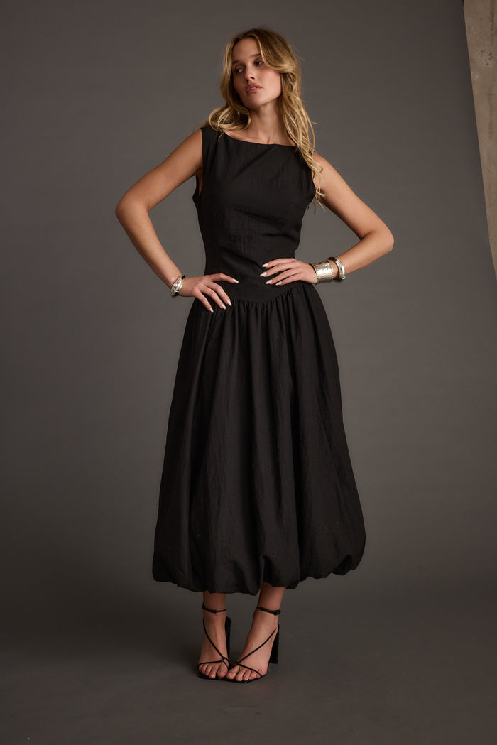 Full-length view of the black midi dress showing the drape and movement.