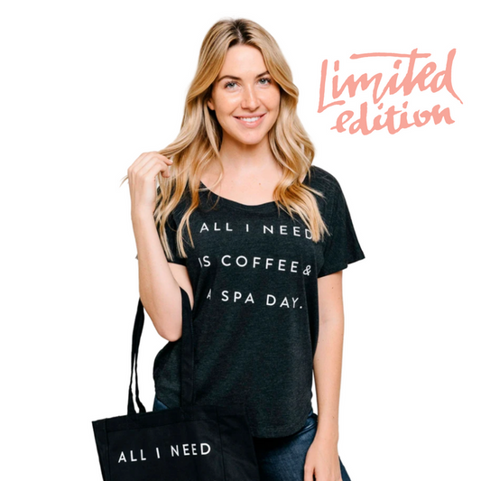 A smiling woman wearing a black Limited Edition Promotion - Coffee and Spa Day dolman tee | Live Love Spa, holding a matching black tote bag with text, promoting wellness and relaxation.