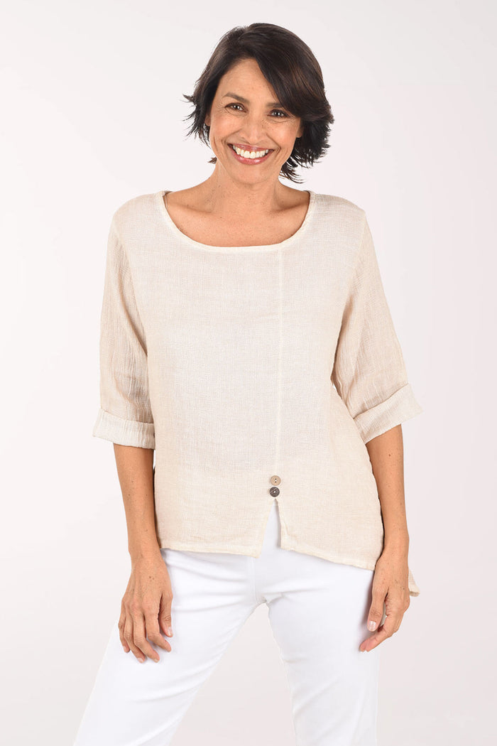 Woman wearing a beige top and white pants on a white background