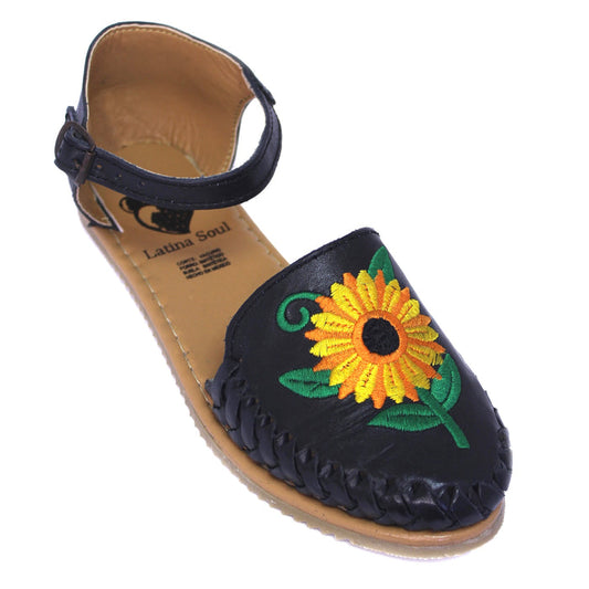 Women's handmade genuine leather huarache sandals featuring colorful embroidered sunflower artwork, woven leather detailing, adjustable ankle buckle strap, cushioned leather footbed, and authentic artisan craftsmanship made in Mexico.