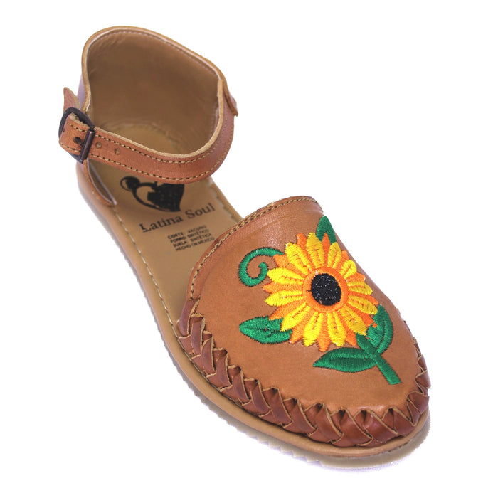 Women's handmade genuine leather huarache sandals featuring colorful embroidered sunflower artwork, woven leather detailing, adjustable ankle buckle strap, cushioned leather footbed, and authentic artisan craftsmanship made in Mexico.