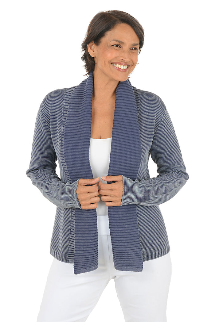 Woman wearing a blue knitted cardigan over a white top on a white background.