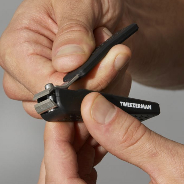 Close-up of hands holding and adjusting a black Precision Grip Toenail Clipper | Tweezerman designed for comfortable and precise toenail trimming.