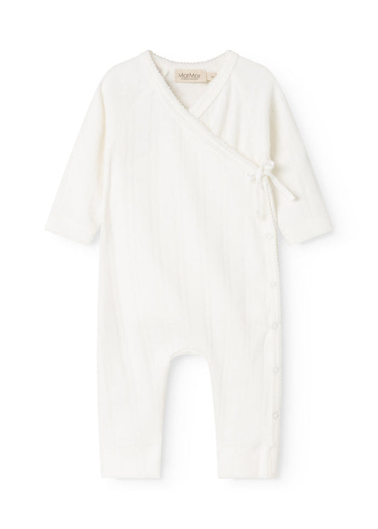 White baby romper with cross-over front and lace detail at the neckline.