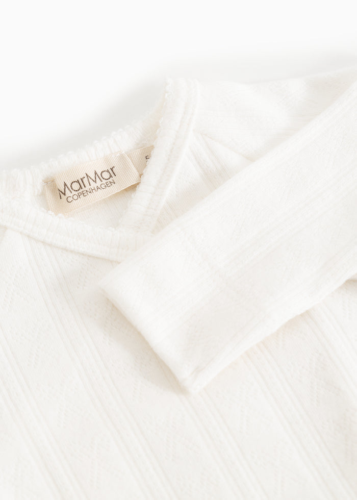 White baby jumpsuit with MarMar Copenhagen brand at the neckline and buttons down the front.