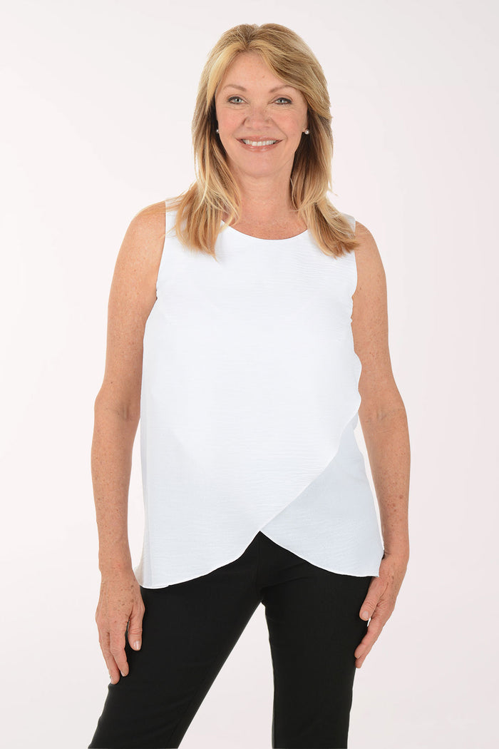 Woman wearing a white sleeveless top and black pants on a white background
