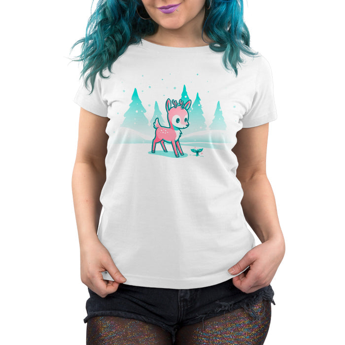 Premium Cotton T-shirt_TeeTurtle white Winter Wonderland apparel featuring a cartoon deer with small antlers stands in a snowy landscape with evergreen trees, looking curiously at a glowing sprout on the ground. Snowflakes are falling around them.